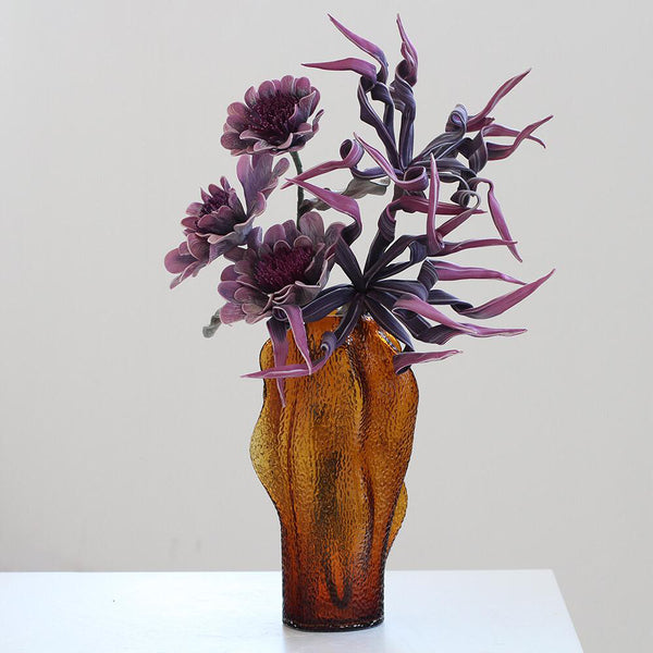 Agnes Amber Textured Vase brought by Heritage Home Design +Living: A tall, textured vase in amber hues, showcasing abstract elegance. Perfect for luxury home decor, with purple florals accentuating its sophisticated charm.